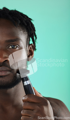 Image of Shaving face with razor, black man in studio and skincare for smooth facial hair on green background. Confident young model grooming, hygiene and cleaning beard with cosmetic morning routine
