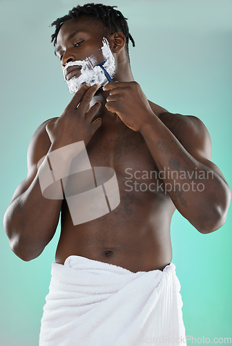 Image of Black man shaving facial hair, skincare cream on studio background and white towel. Happy young model grooming in bathroom, hygiene product and cleaning beard with cosmetic morning routine