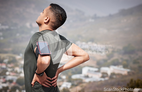 Image of Fitness, pain and man with hands on back, hurt muscle on run with smartphone running tracker. Health, exercise and outdoor workout, runner with injury, tension or painful muscles on marathon training