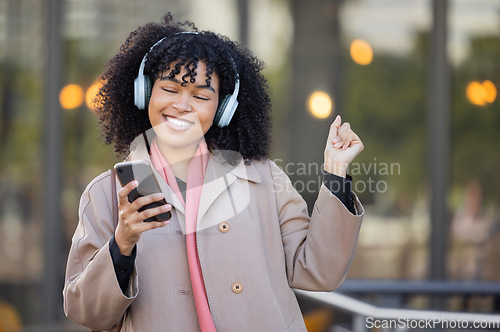 Image of Happy woman listening to music in city, dancing with energy or mental health podcast for travel. Urban student in headphones, smartphone or 5g audio technology, streaming app on her way to university