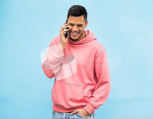 Image of Casual man, phone and laughing on call in communication standing isolated on a blue background. Happy male, person or guys with pink jacket in discussion, conversation or talking on mobile smartphone