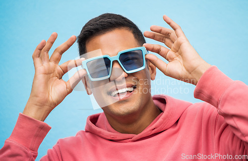 Image of Happy, man with sunglasses and smile with face, trendy fashion and happiness with freedom isolated on blue background. Funky, retro and wellness, hipster person in studio with vintage designer brand