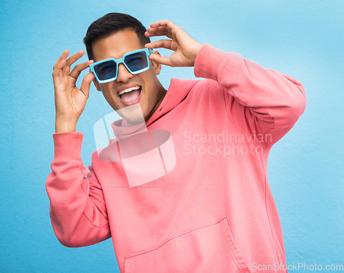 Image of Happiness, man with sunglasses and smile with face, trendy fashion and happy with freedom isolated on blue background. Funky, retro and wellness, hipster person in studio with vintage designer brand