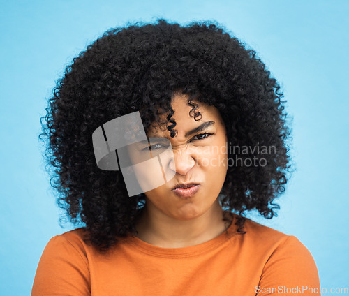Image of Black woman, portrait or angry facial expression on isolated blue background in mental health burnout. Headshot, model or person with mad, annoyed or frustrated face on backdrop mockup with afro hair