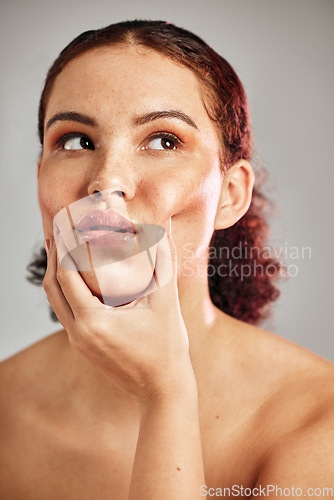 Image of Beauty, natural and real face of studio woman with cosmetics, makeup and healthy skin care glow. Dermatology, spa salon and model girl grabbing cheek for facial massage isolated on grey background