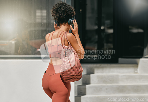 Image of Fitness, headphones or personal trainer walking to gym listening to music to start a workout, exercise or training. Sports girl, back view or healthy black woman traveling or streaming radio audio