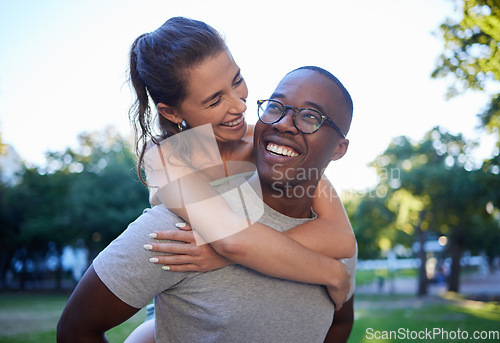 Image of Love, interracial or couple of friends piggy back in a park on fun romantic date in nature bonding together. Relaxing, black man or happy woman laughing or enjoying quality time on a holiday vacation