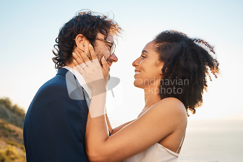 Image of Wedding, love and interracial couple on mountain for marriage ceremony, commitment and celebration by sea. Romantic holiday, happy and bride and groom bonding, hug and smile by ocean with sunset