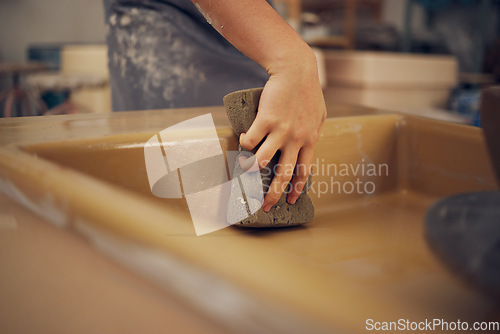 Image of Hand, pottery and sponge with a woman in her workshop or studio to design or manufacture creative ceramic art. Manufacturing, product and cleaning with a female potter wiping a mold while sculpting