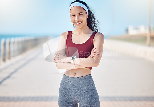 Image of Happy woman, portrait and fitness with arms crossed at beach promenade for exercise, wellness and health in Miami. Female athlete, smile and standing at seaside for workout, summer training or sports