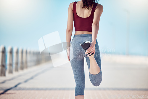Image of Fitness, woman and stretching legs at beach promenade for exercise, wellness and training. Back of athlete, runner and person warm up body at seaside for summer workout, sports and marathon running