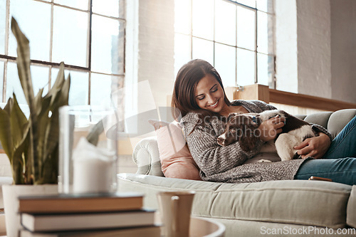 Image of Woman relax on couch with puppy, happy and content at home with pet, happiness together with peace in living room. .Female cuddle dog, love for animals with smile and care, stress relief and comfort