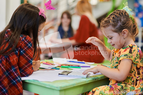 Image of Creative kids during an art class in a daycare center or elementary school classroom drawing with female teacher.