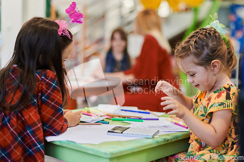 Image of Creative kids during an art class in a daycare center or elementary school classroom drawing with female teacher.