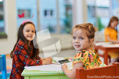 Image of Creative kids during an art class in a daycare center or elementary school classroom drawing with female teacher.