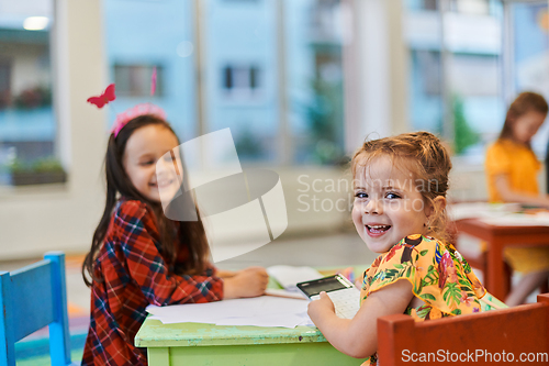 Image of Creative kids during an art class in a daycare center or elementary school classroom drawing with female teacher.