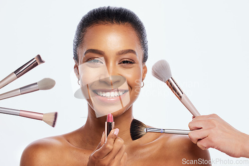 Image of Makeup, beauty brush and lipstick on face of woman portrait in studio for dermatology cosmetics. Happy aesthetic model person with facial tools for healthy skin glow isolated on a white background