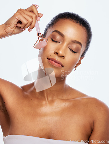 Image of Skin care, facial roller and massage for a woman in studio for dermatology, cosmetic and natural face. Aesthetic model person with spa jade stone tools for healthy glow isolated on a white background