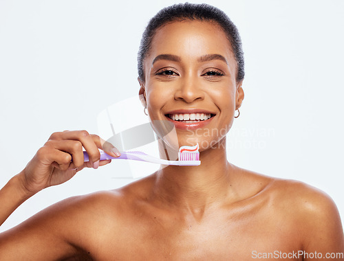 Image of Portrait, dental and a black woman brushing teeth in studio isolated on a white background for oral hygiene. Face, toothbrush and toothpaste with an attractive young female posing on blank space