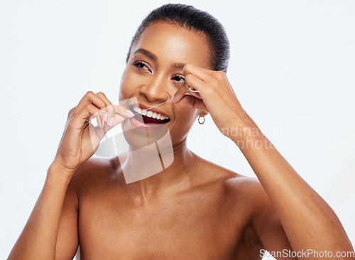 Image of Dental hygiene, floss and black woman cleaning mouth, wellness and studio background. African American female, lady and oral health with string for teeth, remove plaque from tooth enamel and cavities