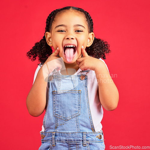 Image of Little girl, portrait and tongue out on isolated red background in goofy, silly games and playful facial expression. Happy, kid and child with funny face in comic emoji, charades and studio activity