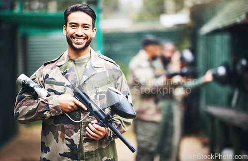 Image of Paintball, gun and portrait of a man soldier in a camouflage military outfit for extreme sports. Happy, smile and male player in army clothes with a pistol preparing for a match in an outdoor arena.