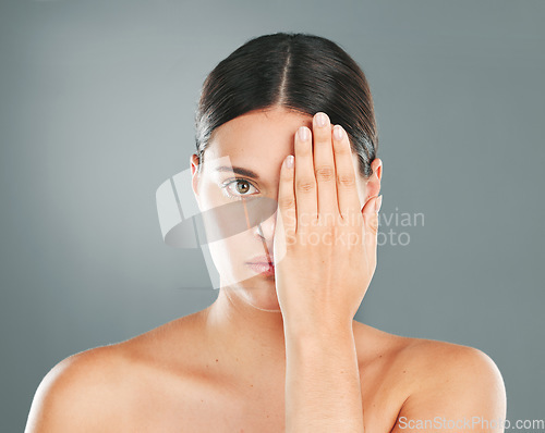 Image of Face, cover and portrait of a woman with a hand on eye isolated on a grey studio background. Skincare, beauty and serious model hiding eyes for dermatology, botox problem and cosmetics on a backdrop