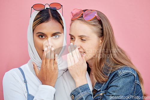 Image of Woman, friends and secret whisper of gossip in shock against a pink studio background. Women sharing secrets, rumor or surprise whispering in the ears for hidden story, sale or discount announcement