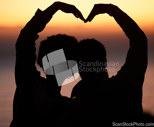 Image of Sunset, heart and silhouette of couple at beach enjoying romantic vacation, holiday and honeymoon adventure. Emoji, travel and shadow of people relax, calm and together for trust, commitment and love