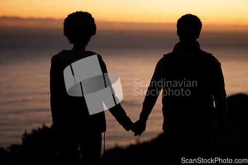 Image of Sunset, beach and silhouette of couple holding hands for date by the sea with dark shadow, love and care. Horizon, ocean and people rear with together in nature for hiking or travel goals on holiday