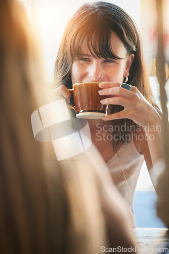 Image of Woman, friends and drinking coffee for conversation, chatting about social life or gossip at an outdoor cafe. Happy female smiling and enjoying a warm beverage, discussion or listening to best friend