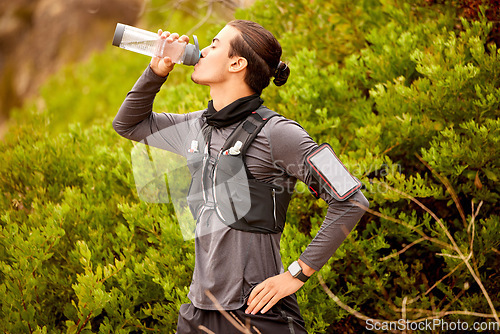 Image of Man, runner fitness and drinking water outdoor for hike, cardio training or exercise workout. Athlete, sports break with bottle drink and sports wellness running in nature park or mountain hiking