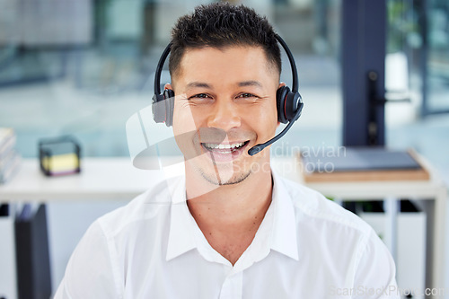 Image of CRM, portrait and Asian customer service employee happy to be working telemarketing in the office. Support, help and man agent, consultant or worker smiling on an online video call using a headset