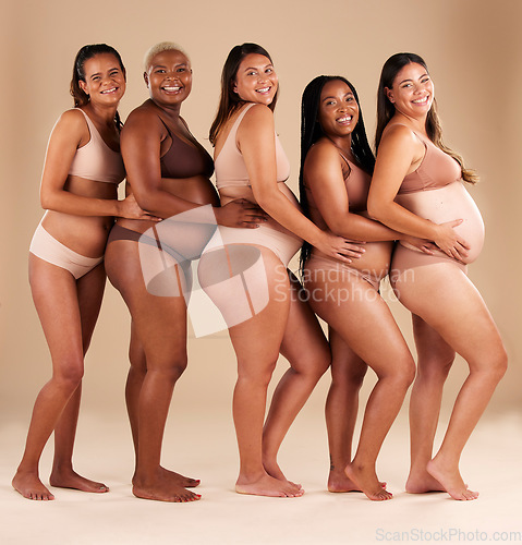 Image of Portrait, pregnant and happy women in row on studio background in community, diversity or baby support group. Smile, happy or bonding mothers with pregnancy stomach, underwear or healthcare wellness