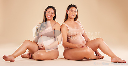 Image of Women, portrait or sitting with pregnant stomach, tummy growth progress or baby healthcare wellness on studio background. Smile, happy or friends in pregnancy underwear for solidarity support or love