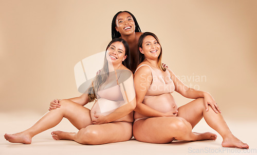 Image of Happy women, portrait and sitting and pregnancy stomach, belly growth or baby healthcare wellness on studio mock up. Smile, diversity and friends on floor in pregnant underwear or solidarity support