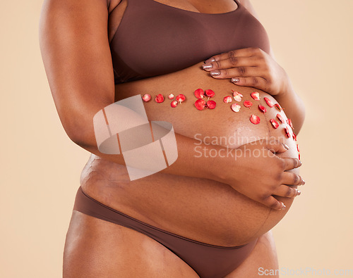 Image of Pregnant woman, flowers and stomach in studio background of body, maternity and healthcare. Closeup abdomen, floral plants and pregnancy glow of mother, belly skincare and gynecology of natural birth