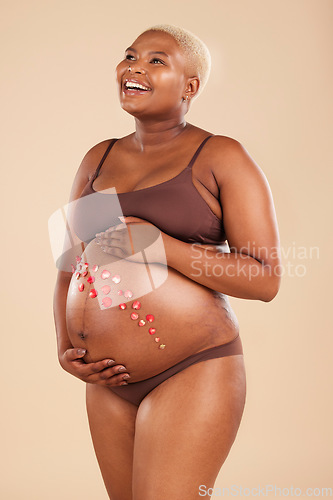 Image of Pregnant, black woman and smile with flowers on belly in studio for body, baby wellness and ivf healthcare. Mother, pregnancy and floral plants on stomach with happiness, beauty or natural childbirth