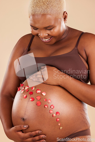 Image of Pregnant woman, smile and flowers on stomach in studio, body and baby wellness of ivf healthcare. Mother, pregnancy and floral plants on abdomen of happiness, beauty or excited for natural childbirth