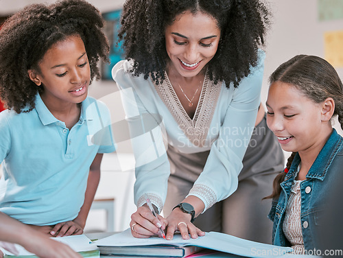 Image of Helping students with homework, female teacher in classroom with children listening and writing in book. Diversity in education, educator reading kids notebook and group learning literature together