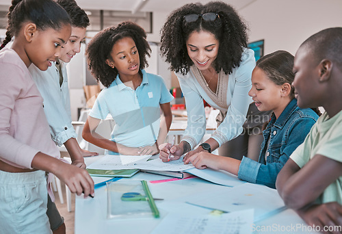 Image of Female teacher in classroom with students, helping learner with homework and writing in book. Childrens education at school, educator reading kids notebook and group learning together for assessment