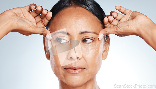 Image of Skincare, beauty and senior woman thinking of wrinkles isolated on a grey studio background. Worry, cosmetic and face of a mature model feeling skin for anti aging, concern and idea on a backdrop