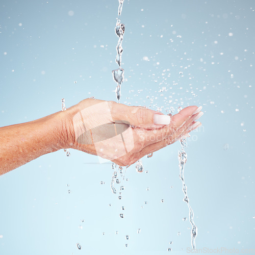 Image of Senior hands, water splash for clean hygiene, fresh sustainability or wash against studio background. Hand of elderly holding natural liquid drops for skin hydration, wellness or safety from bacteria