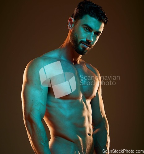 Image of Sexy male model, nude in neon lighting aesthetic in studio with creative dark background and sensual pose. Confident man with strong body, artistic creativity with trippy lights and abs on bare chest