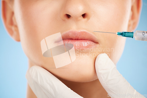 Image of Botox, facial and lip filler by woman with cosmetic injection isolated against a studio blue background. Beauty, beauty and closeup of girl get plastic surgery at a cosmetology clinic using a syringe