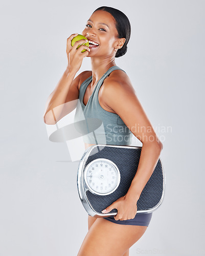 Image of Portrait, scale and black woman eating apple on diet for weightloss, workout and health lifestyle. Fitness, nutrition and body wellness, healthy girl isolated on white background in studio with fruit