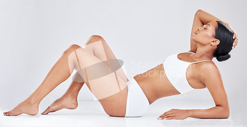 Image of Skincare, beauty and woman in underwear relaxing and lying down on her back isolated in studio white background. Body, dermatology and slim African female model with natural skin posing for wellness