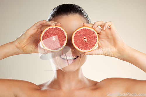 Image of Beauty, skincare and woman cover grapefruit for natural skin dermatology or cosmetic product. Vitamin c fruit on happy face aesthetic model in studio for sustainable self care for health and wellness