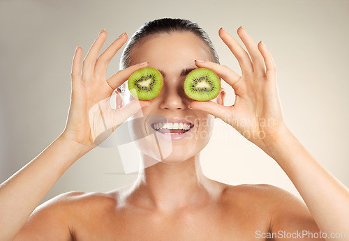 Image of Kiwi fruit, skincare and cover beauty by a woman with natural dermatology cosmetic product. Healthy glow on face of aesthetic model in studio for sustainable spa facial mask for health and wellness