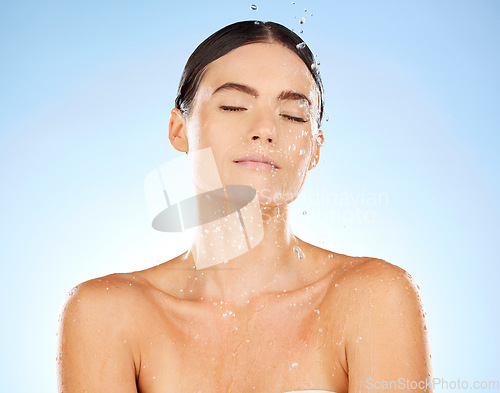 Image of Shower, water and woman cleaning skin for beauty and cosmetic skincare isolated in a studio blue background. Facial, splash and female model washing as body care for hygiene, dermatology and wellness